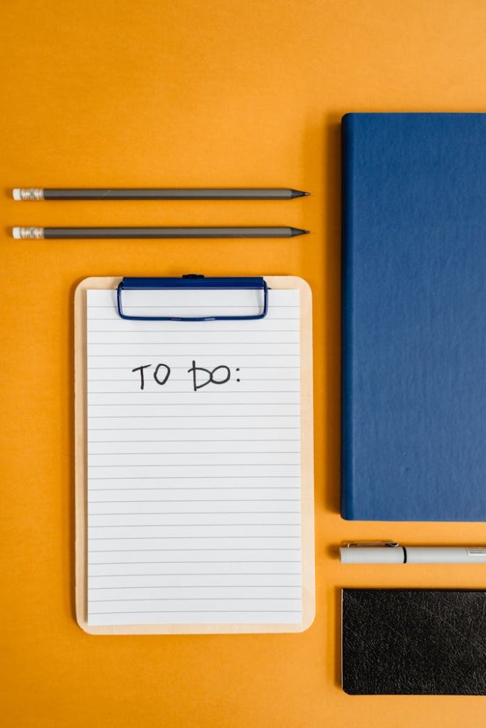 Flat lay of stationery items including notebook, notepad, and pencils on an orange background for productivity themes.